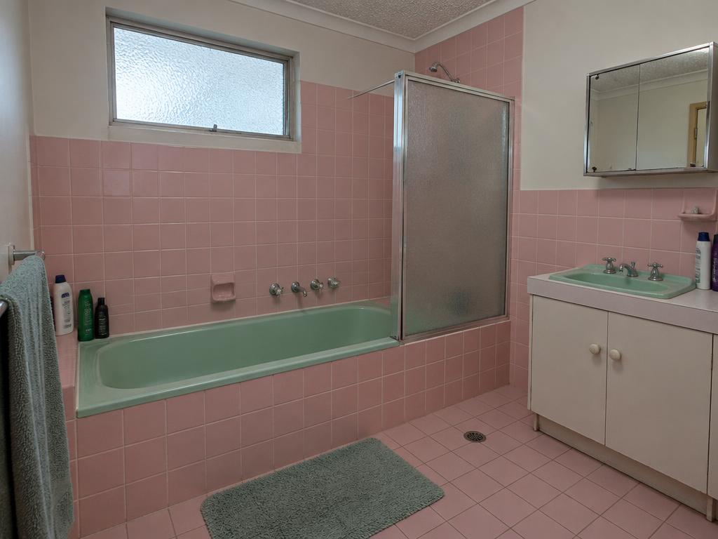 Bathroom before renovation with mint-green bath and pink surround tiles
